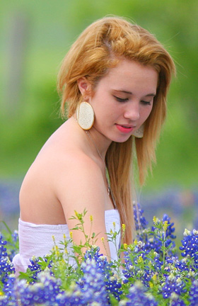 Girl gets her picture taken with Bluebonnets in Brenham Texas.